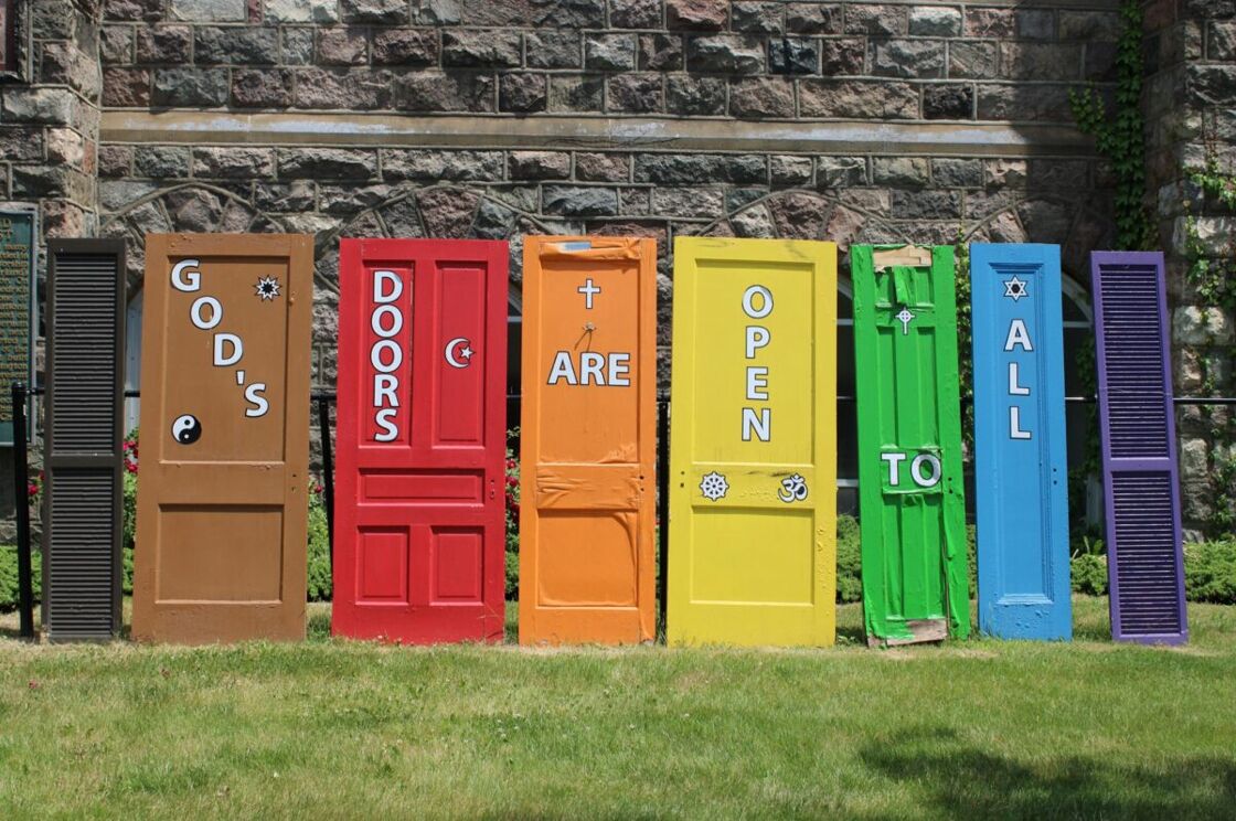 Seven doors in a different color of the rainbow, each featuring different religious sybmols and the words 'God's doors are open to all