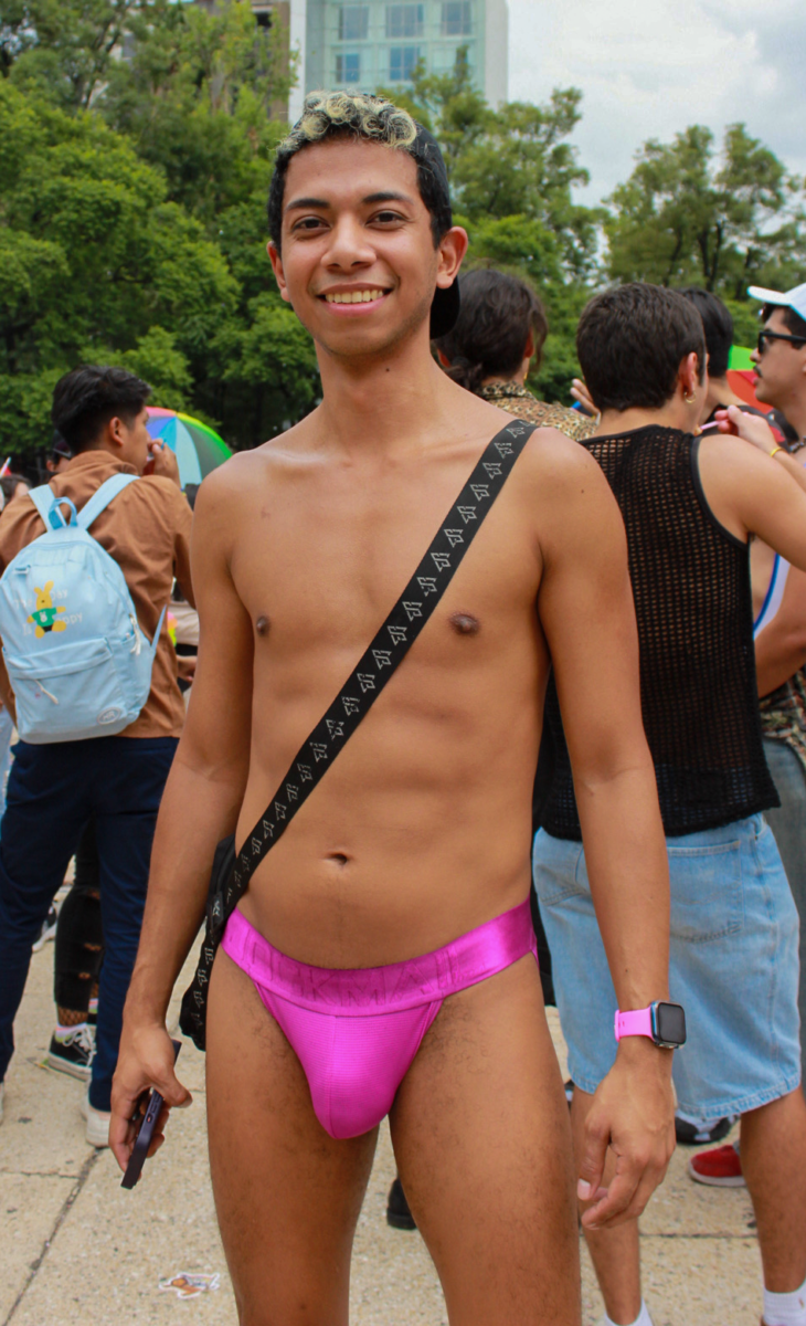 A young Latino man wearing pink underwear poses for the camera.
