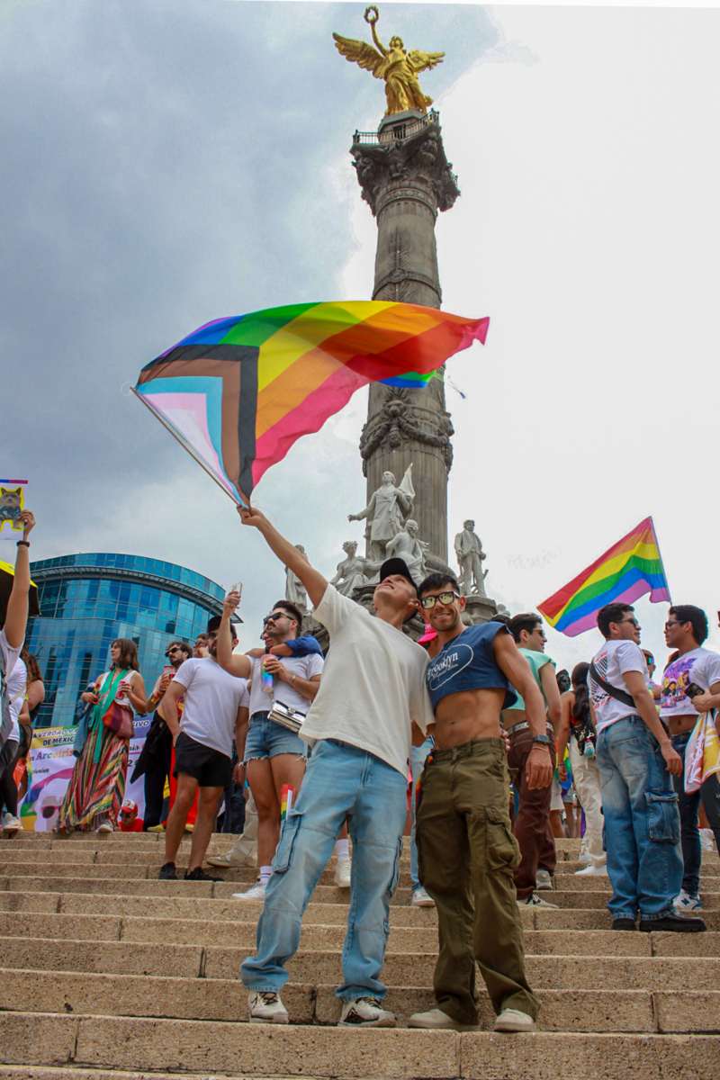 Proud and joyful gay couple celebrating with one of the symbols of Mexico on the back, El Ángel de la Independencia.