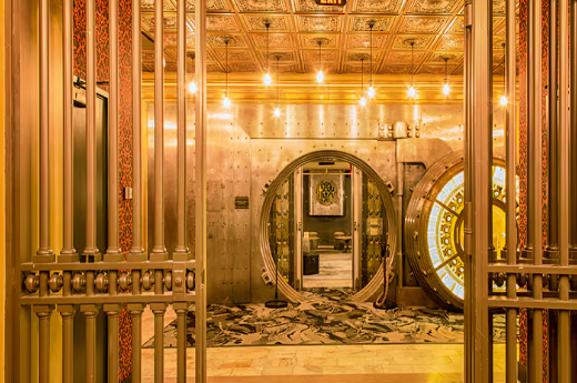 View of a gorgeous renovated bank vault lit by golden light. Photo via Metropolitan at The 9.