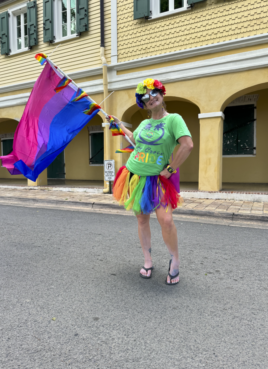 A woman in a rainbow tutu waving the Bisexual flag. 