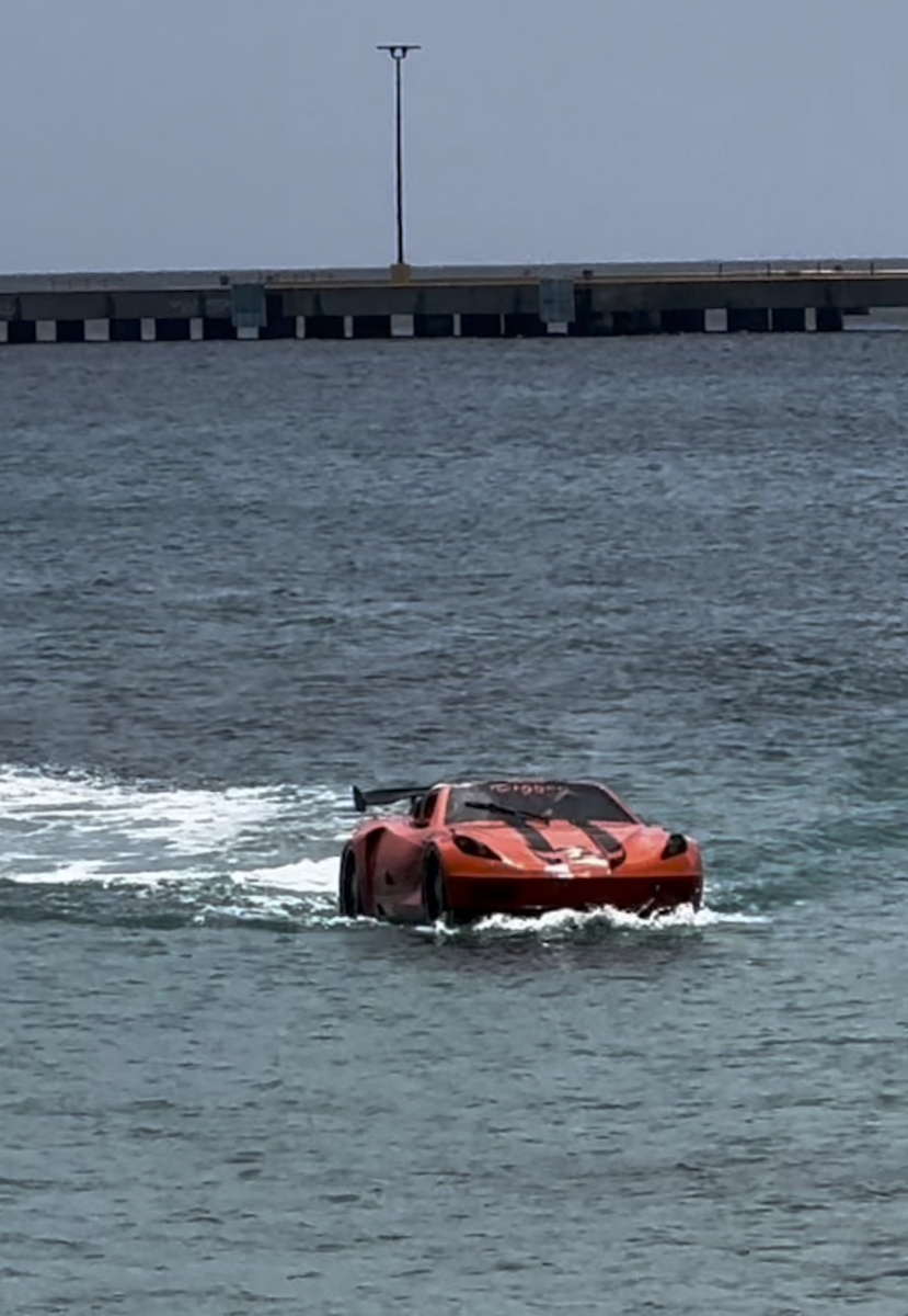 A convertible car speedboat riding through the ocean. 