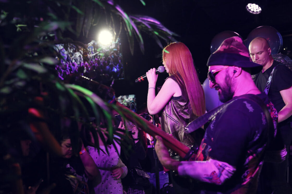 A woman singing on mic with band behind her.