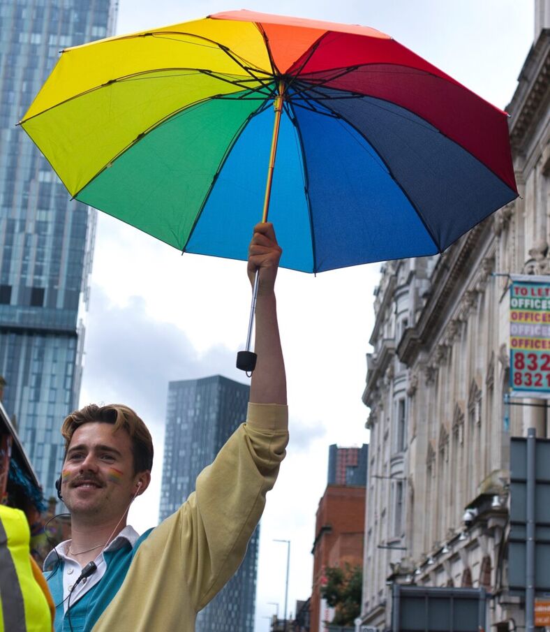 A man holds a rainbow umbrella at Manchester Pride.