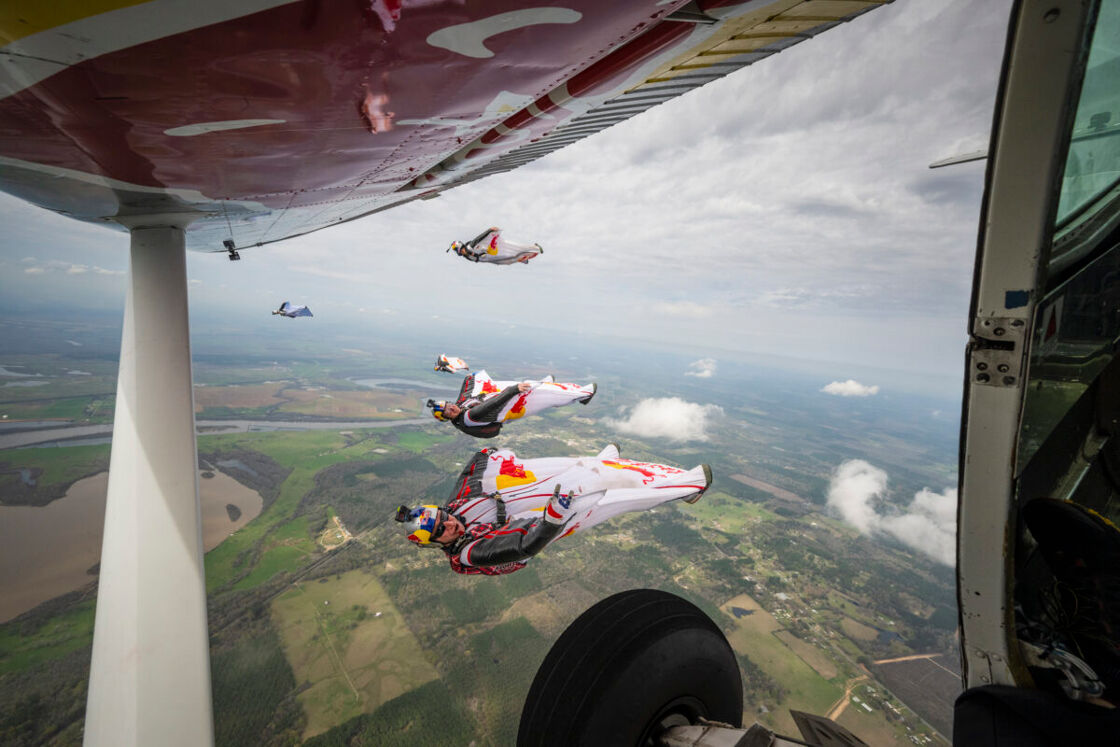 Four people wingsuit fly over the resort