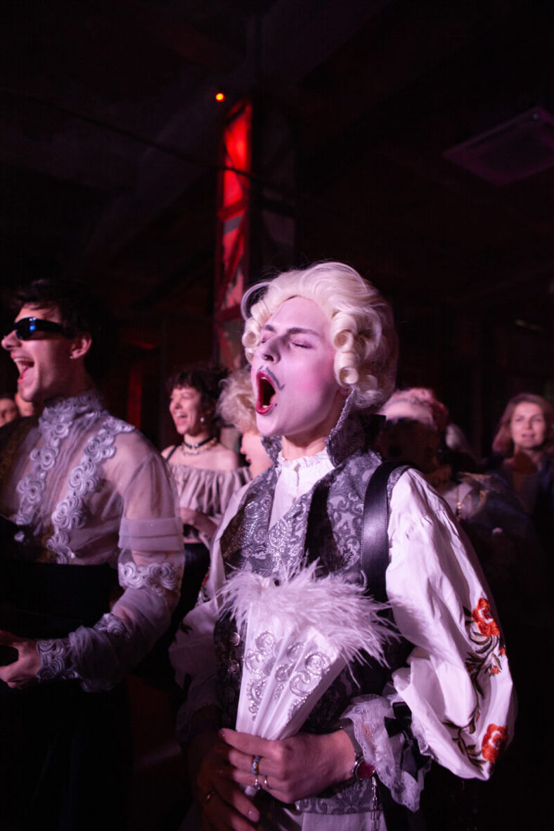 A ball attendee screams their support as participants walk