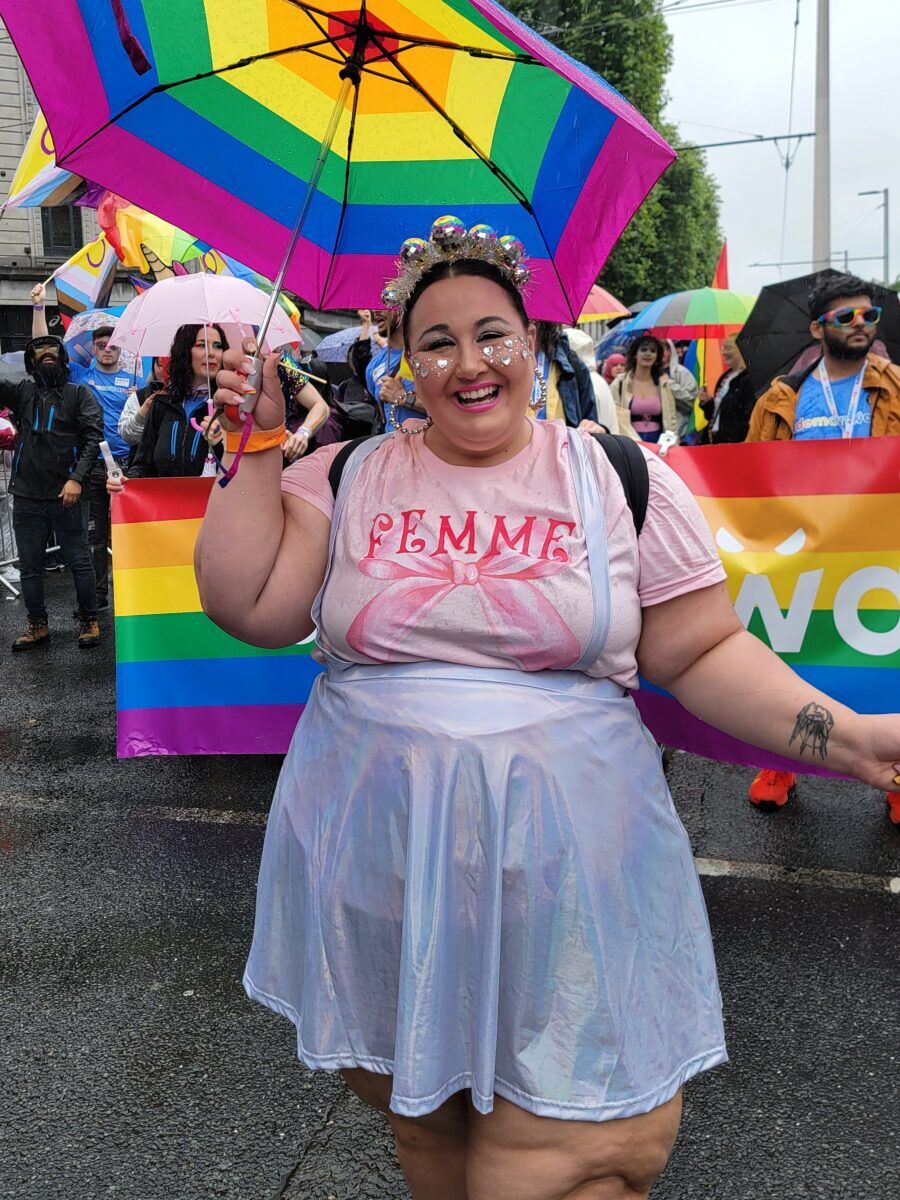 A woman with fun accessories and a rainbow umbrella