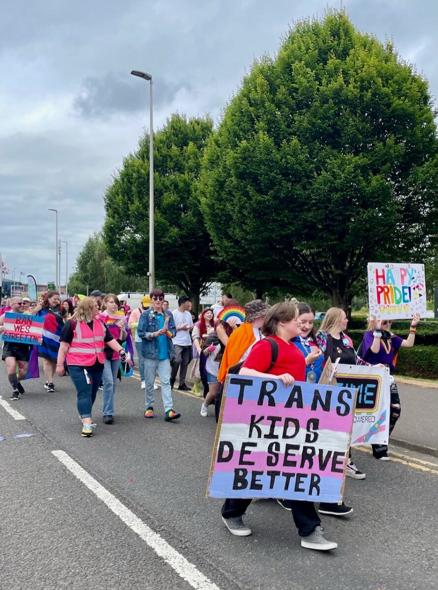 A group of marchers with one woman holding a sign that says, "Trans kids deserve better."