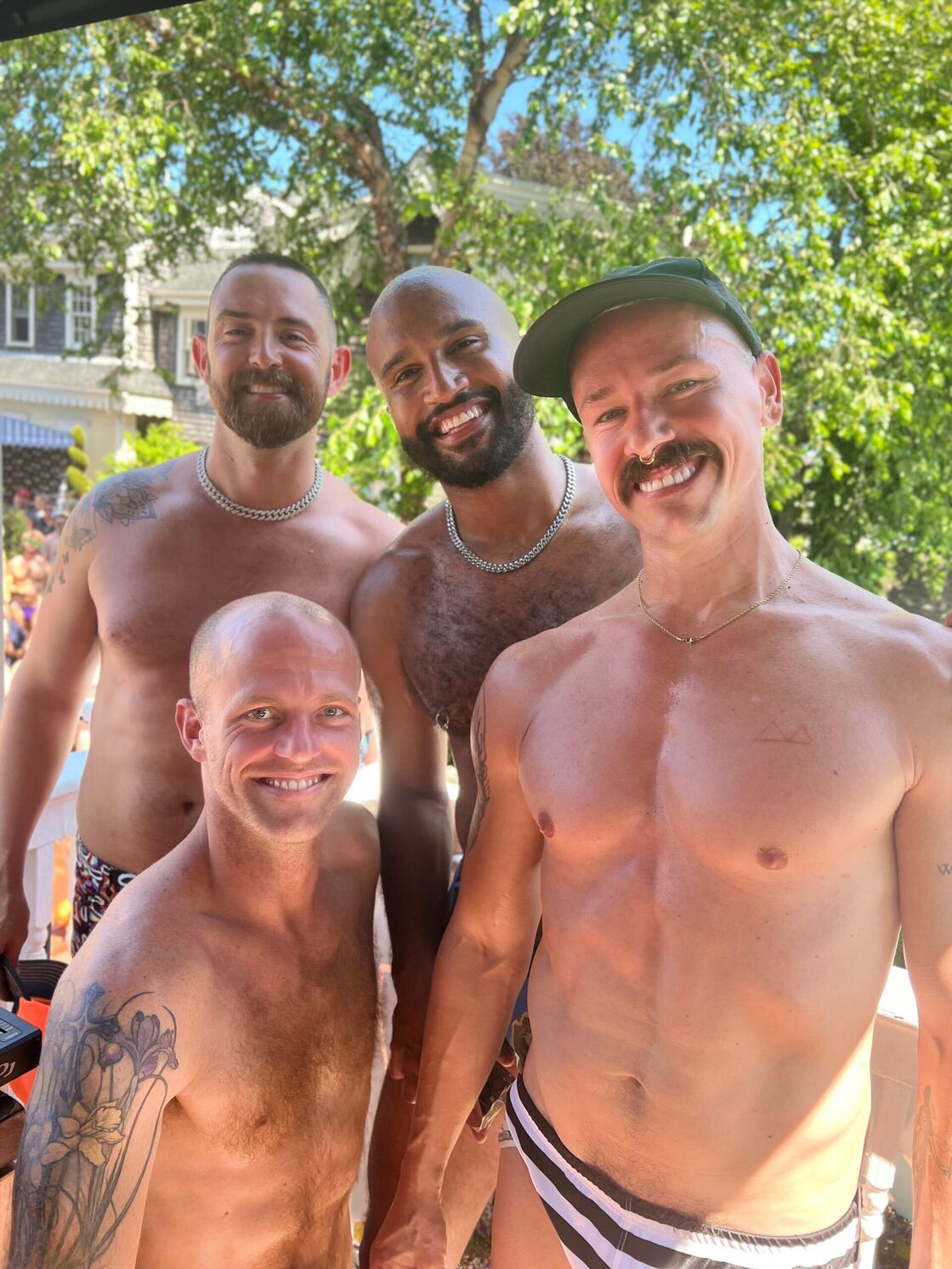 Four shirtless men pose for the camera