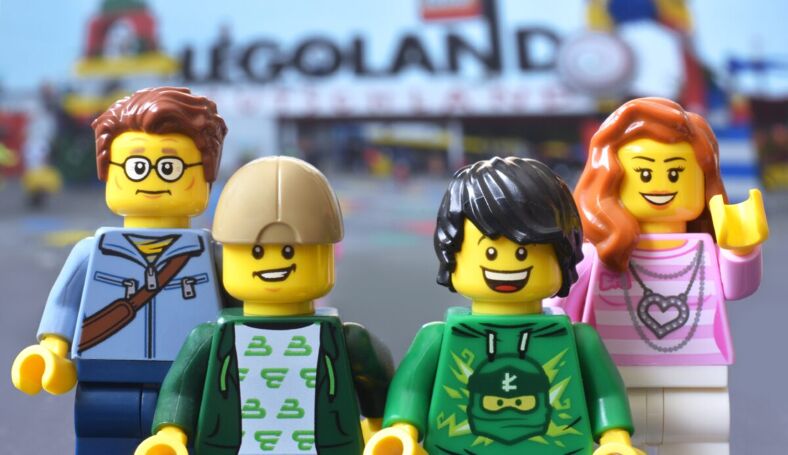 Four Lego figurines posing in front of the Legoland sign.