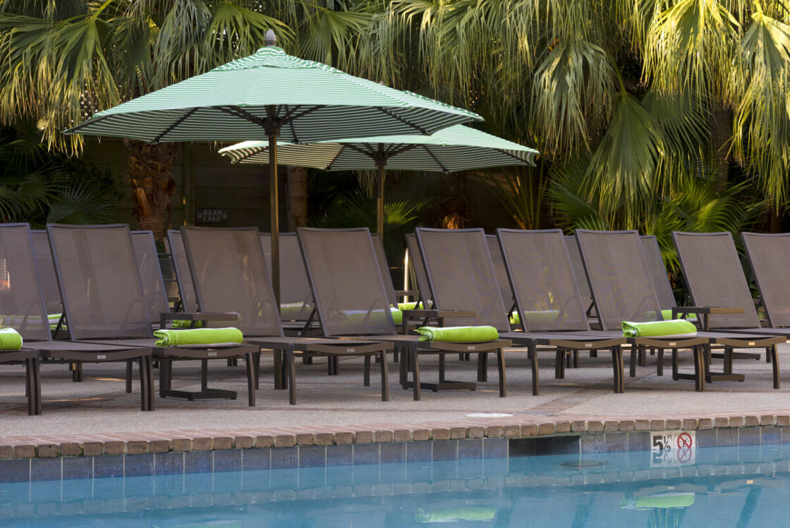 A line of pool chairs under an umbrella