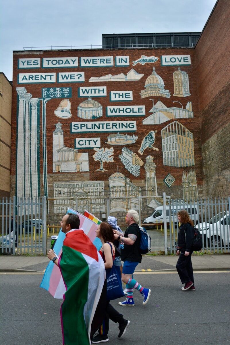 Marchers pass a building mural that reads 