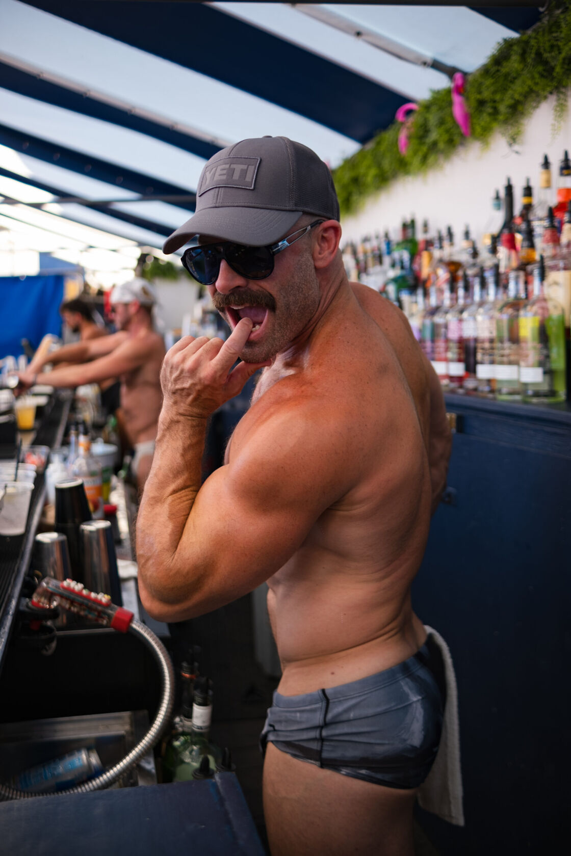 Man flexing his arm muscles by the poolside.