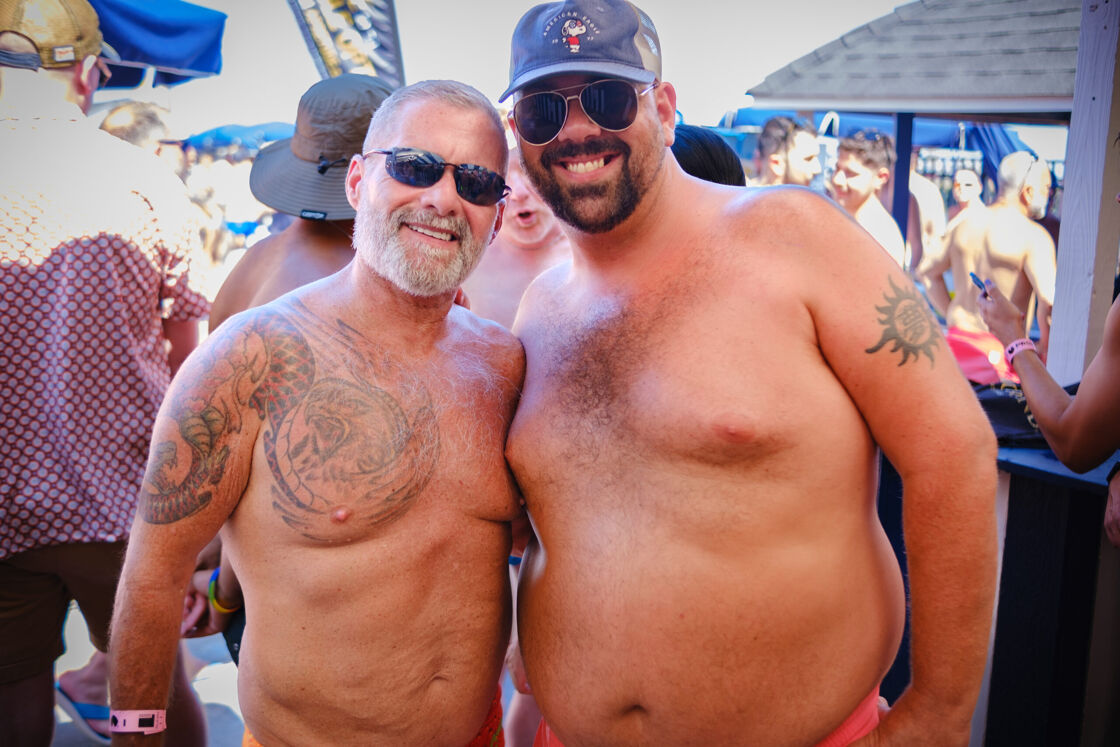 Two men posing together at a pool party.