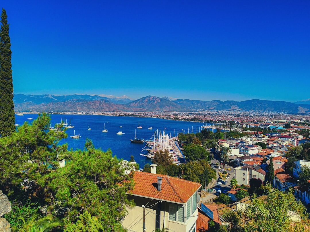 a city with a body of water in the background A view of Fethiye, Turkey, showing the bay and houses