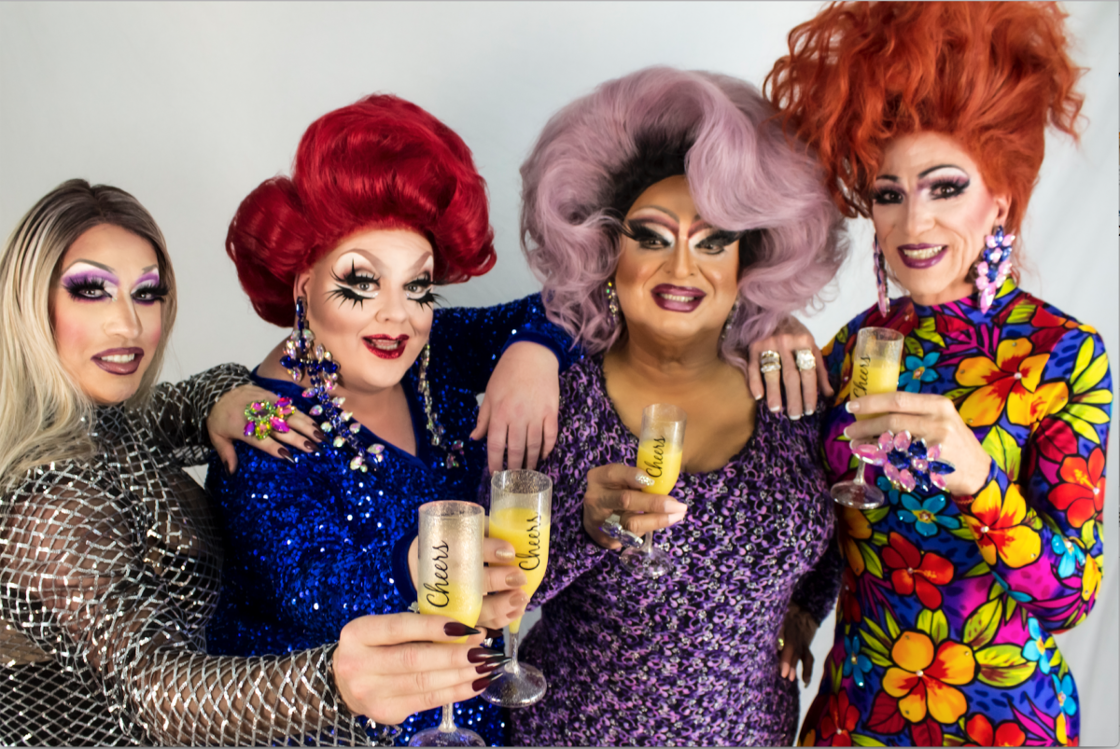 Four drag queens holding champagne glasses