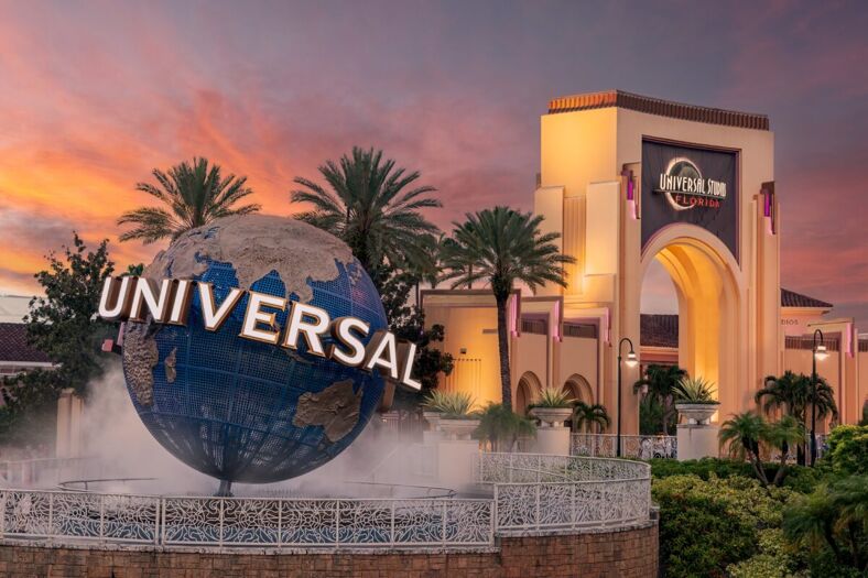 Universal Studios Florida entrance with the iconic globe and palm trees at sunset.