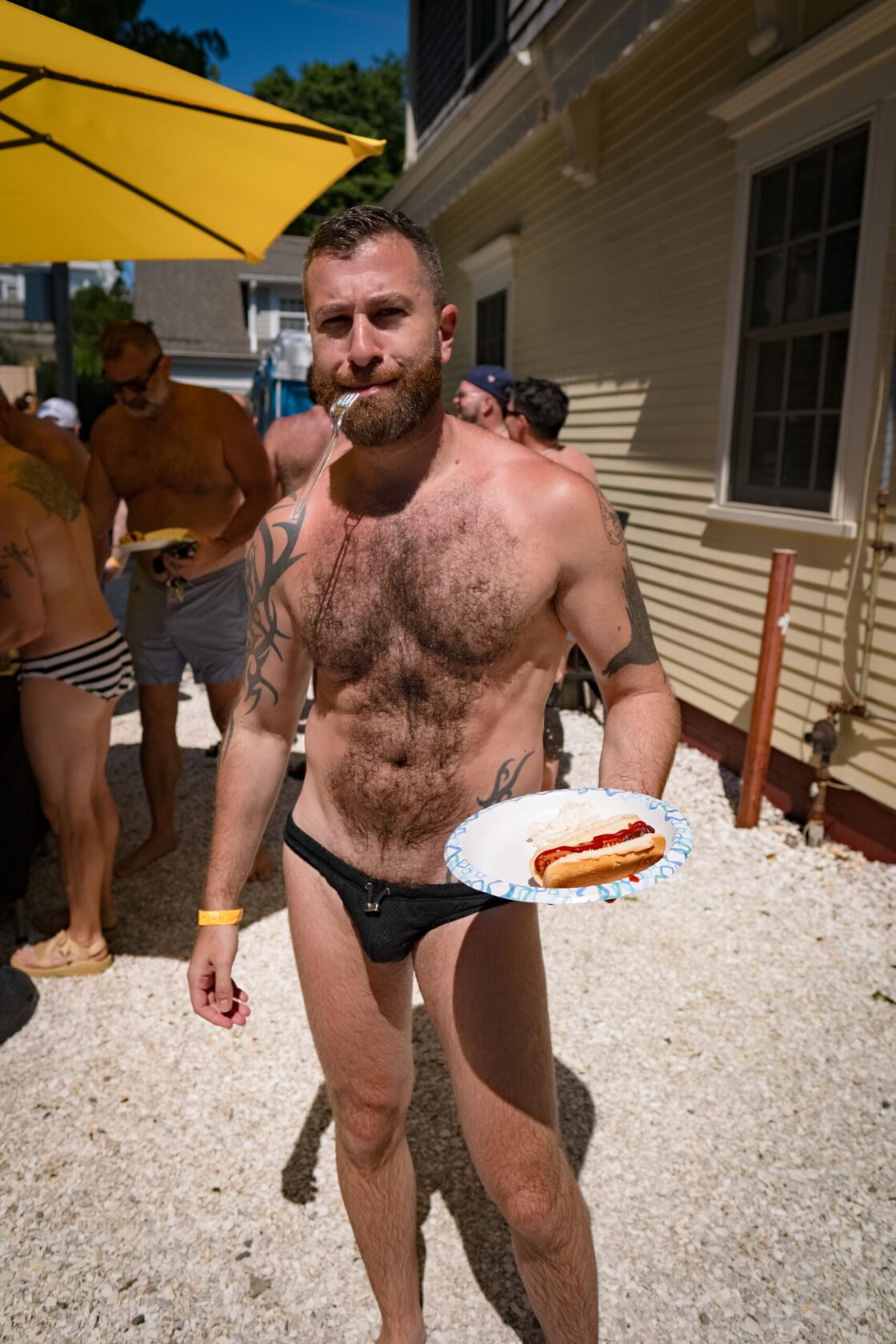 Man holding a plate of food in a Speedo.