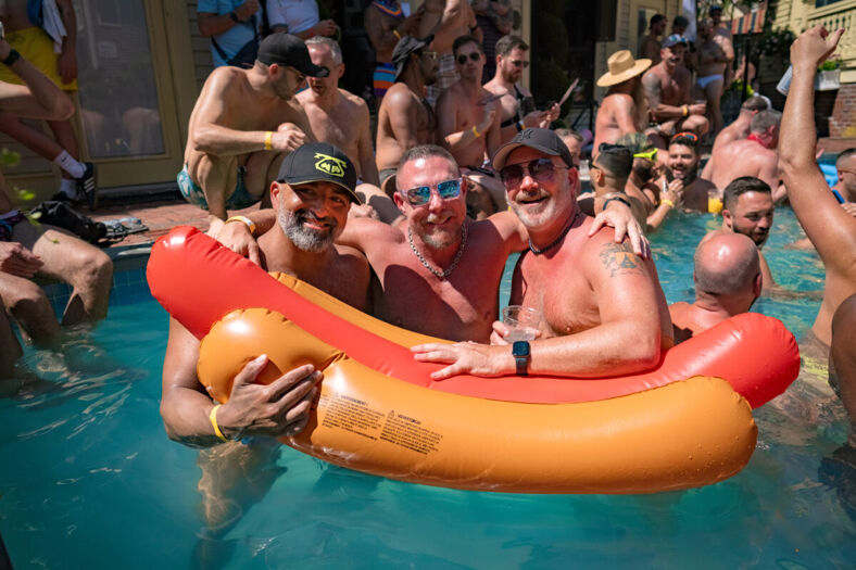 Three men in a pool with an orange float ring.