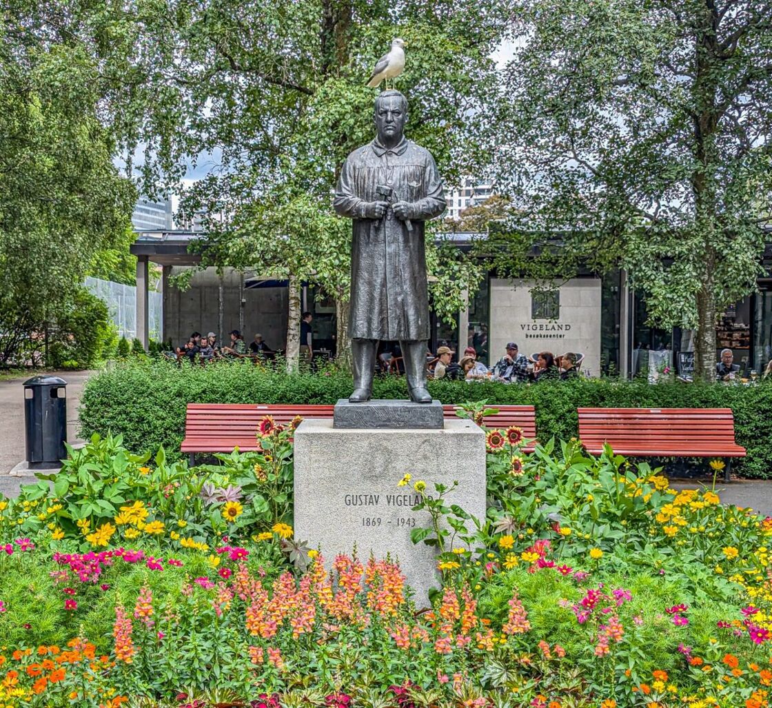 Bronze sculpture of Vigeland in the park surrounded by flowers A statue at Vigeland Sculpture Park