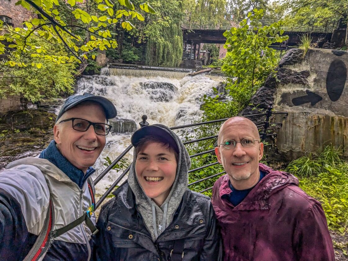 Michael, Marianne, and Brent standing in the rain in front of a waterfall. Me and Brent with Marianne in the middle.
