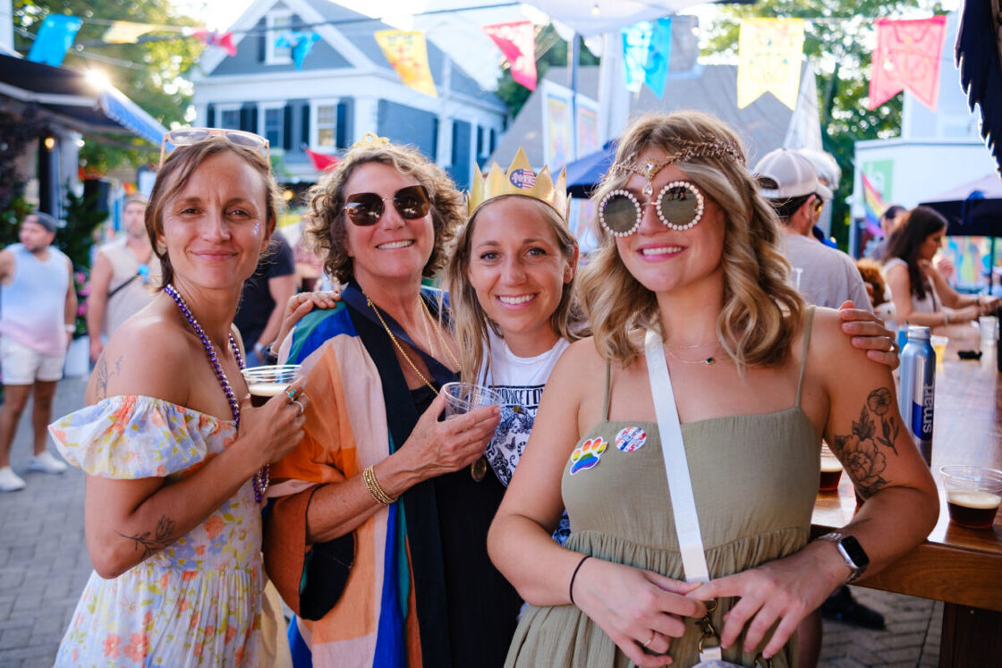 A group of women smile and embrace in the lively street