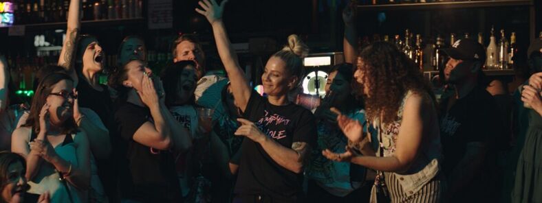 A crowd of women celebrate and dance inside a lesbian bar