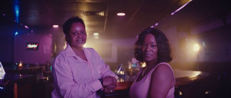 Two Black women pose inside a lesbian bar