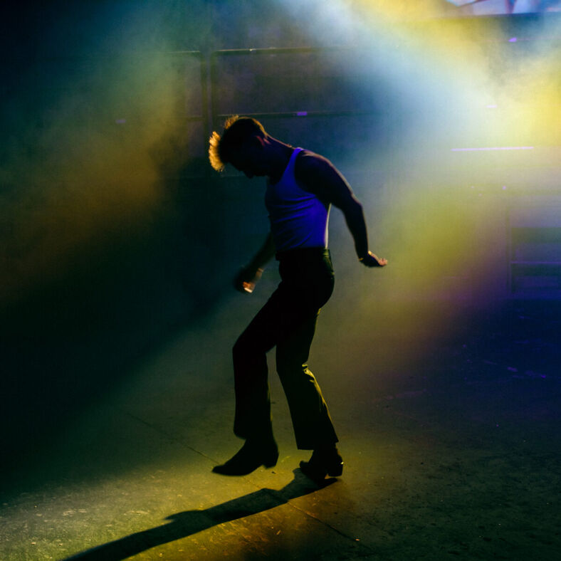 A dancer silhouetted by a yellow light