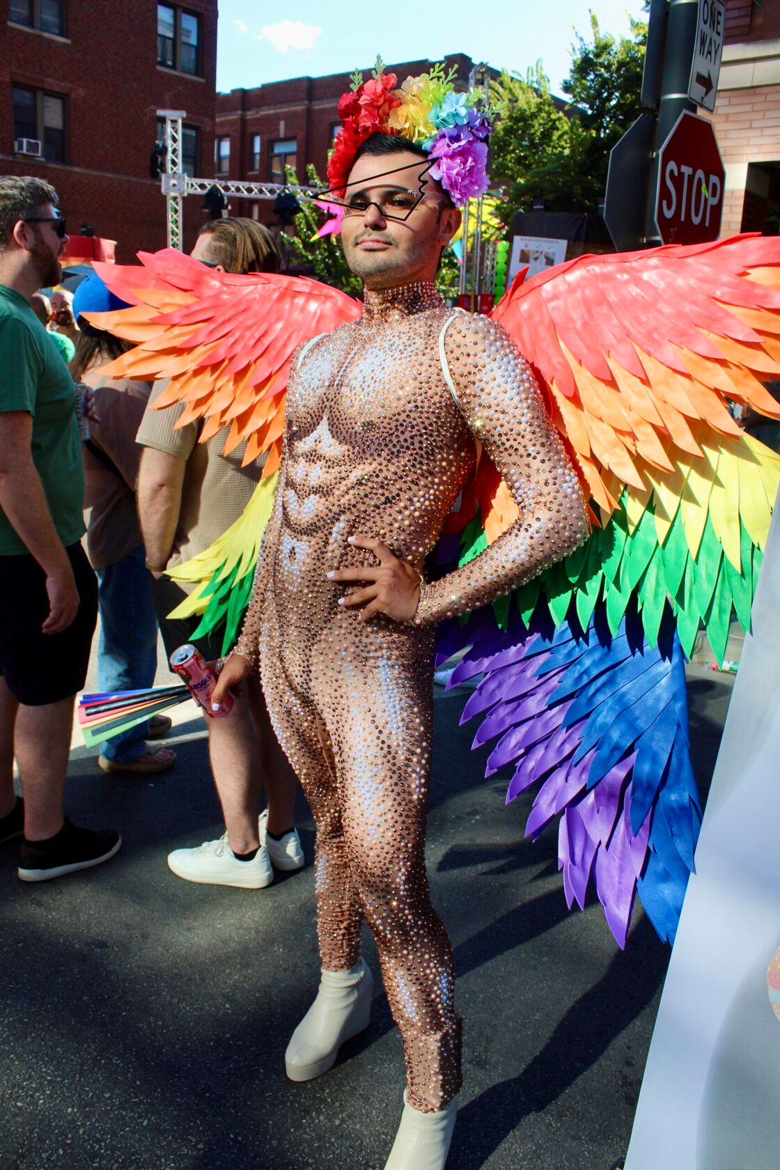 A man wearing rainbow colored wings and a glittery gold bodysuit