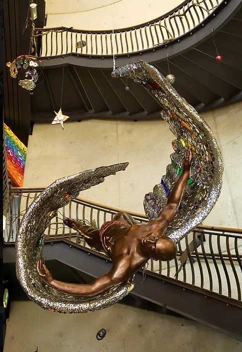 A bronze statue of a shirtless man with glittering mosaic wings falls through the main staircase. 