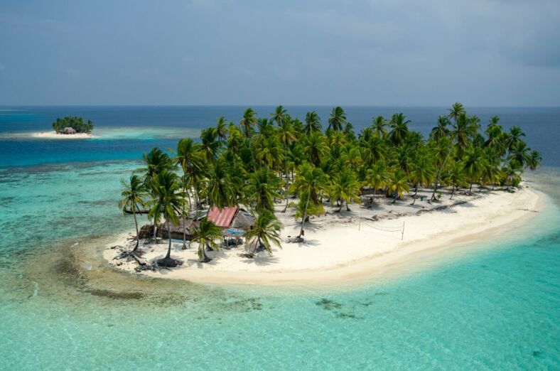 Aerial view of thatched houses and palm tree forest in island. San Blas archipelago