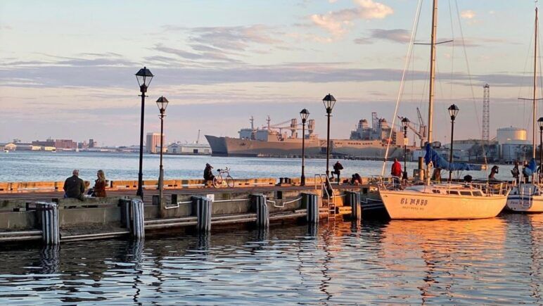 Beautiful shot of the Baltimore harbor and pier at sunset. There are several large ships in the background