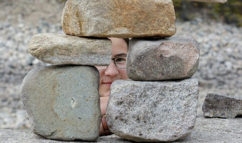 A child peeks through a pile of rocks