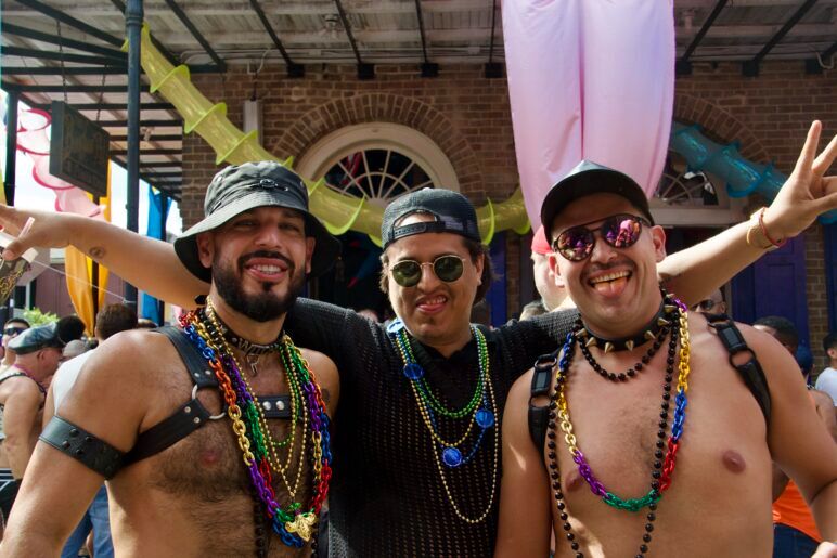 Three friends smile and stick their tongues out playfully at the camera. 