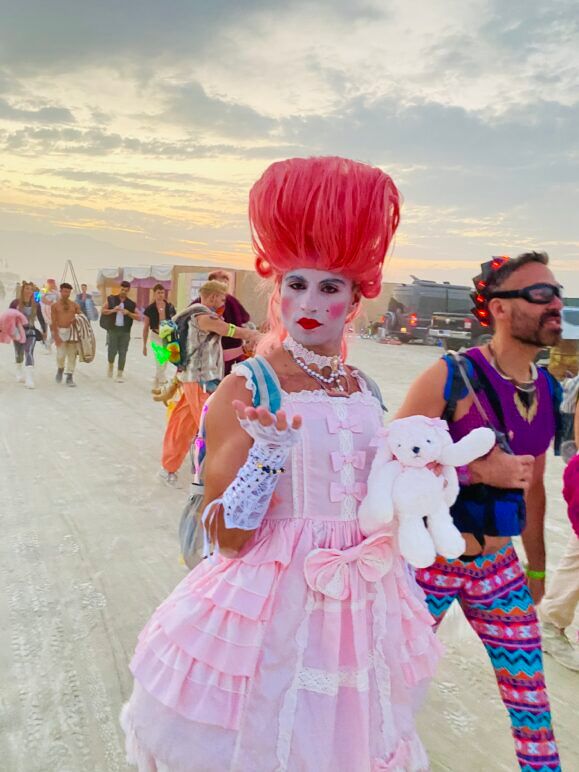 Badger, clad in his nod to Marie Antoinette, leads a procession of his fellow Glamcock campmates towards the Man Burn.