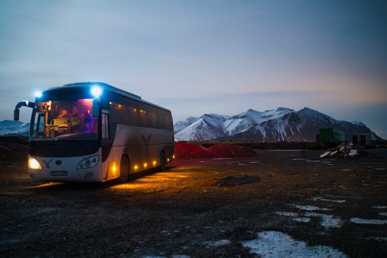 white and black bus running near the mountain white and black bus running near the mountain