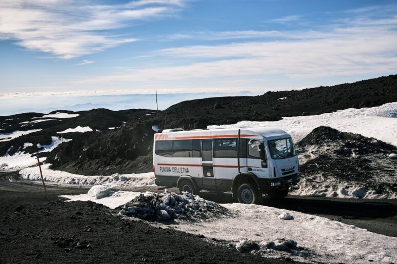 a white bus driving down a snow covered road a white bus driving down a snow covered road