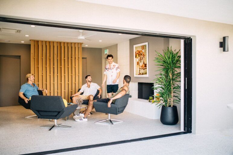 A group of four men sit around talking