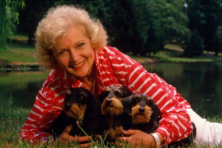 Betty White poses with three puppies