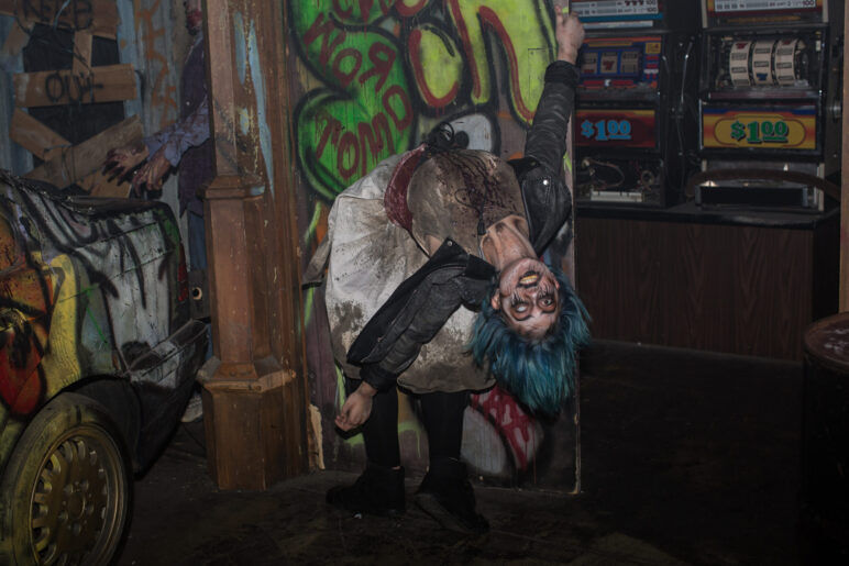 A spooky girl with blue hair and scary makeup does a terrifying backbend