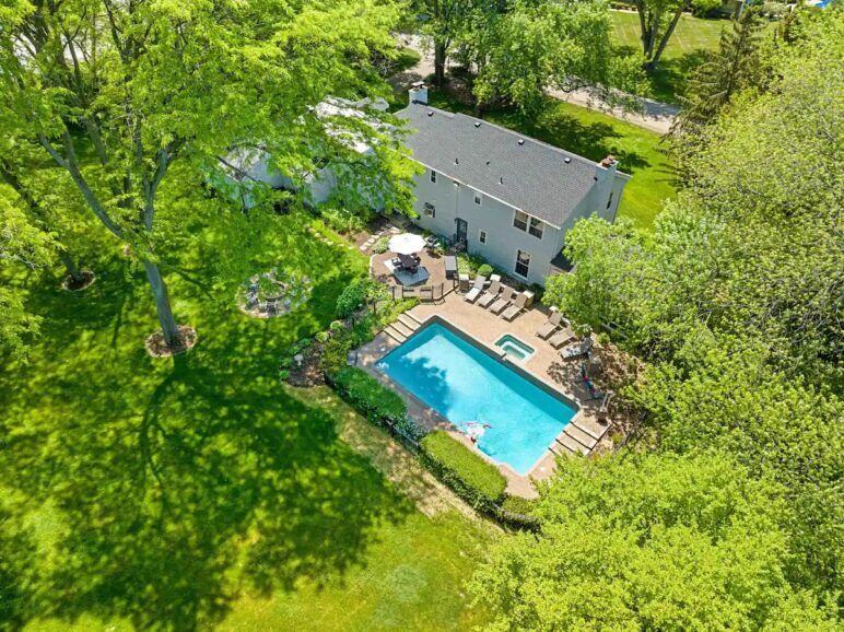 Trees and lawns surround a pool in an arial shot of an estate in Chicago