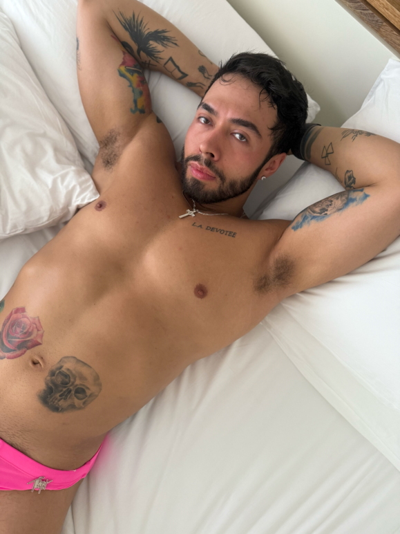 Amaya poses in bed wearing a pink speedo