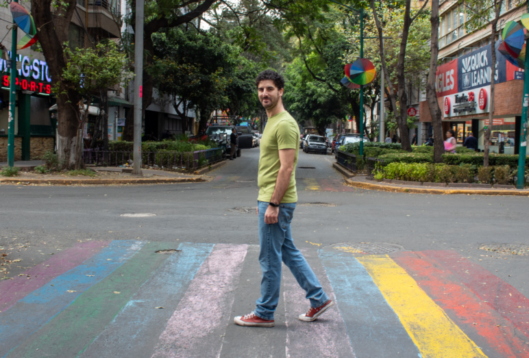 Chapu Garza walks across a rainbow crosswalk