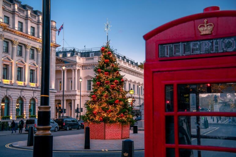Christmas scene outdoors in London, with decorated tree and red colorful holiday lights on the street
