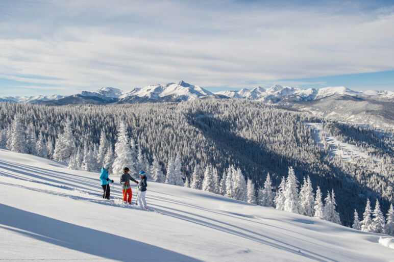 Three people talk on the side of a snowcovered mountain