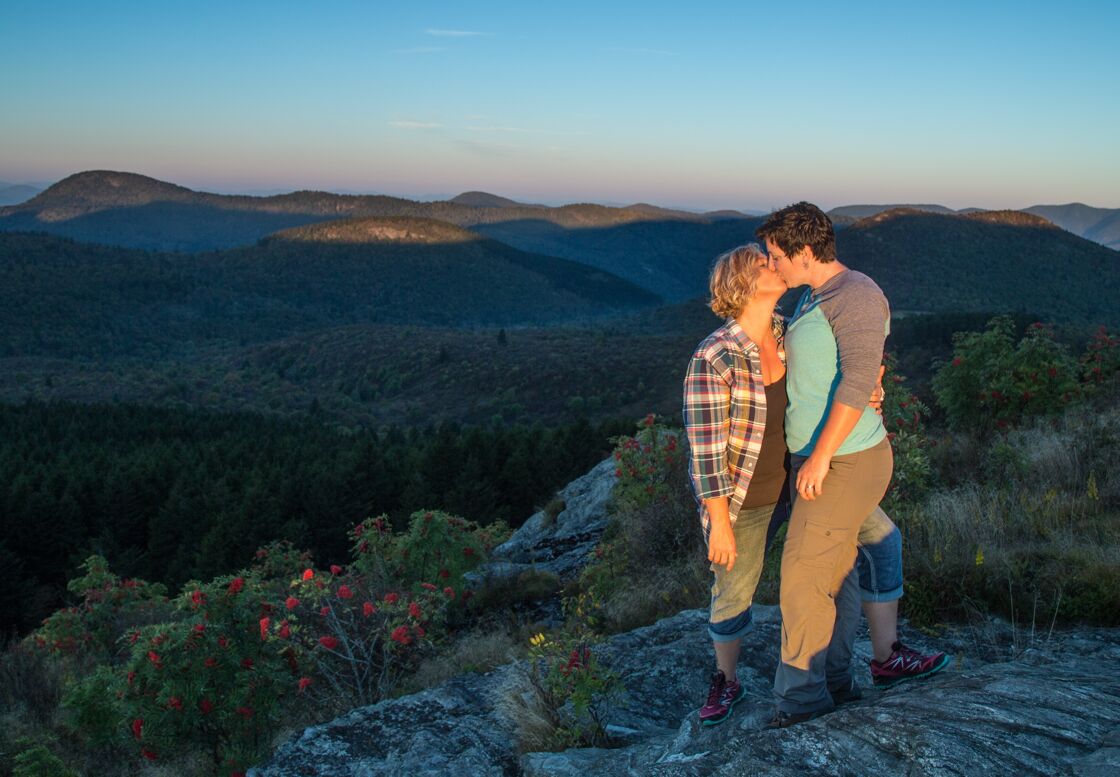 An LGBTQ+ couple kisses while hiking in Asheville.