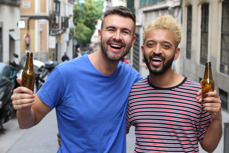 Two cheerful men drinking beer outdoors