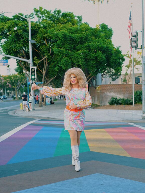 Drag laureate Pickle stands on a crosswalk painted with the Pride flag in West Hollywood