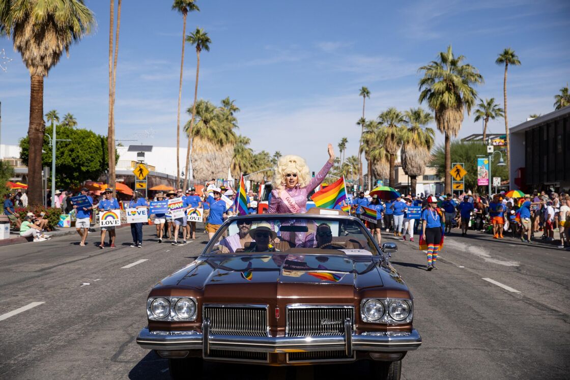 A drag queen rides in a vintage car at Palm Springs Pride